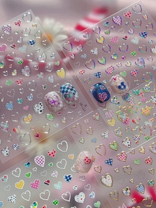 Macro shot of silver heart nail stickers with colorful patterns and laser borders