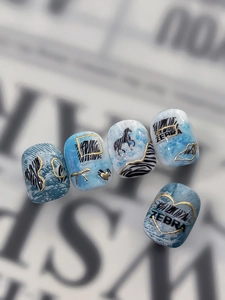 Detail of blue marble press-on nails with golden zebra stripes and heart patterns