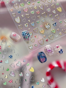 Macro shot of silver heart nail stickers with colorful plaid and gradient patterns