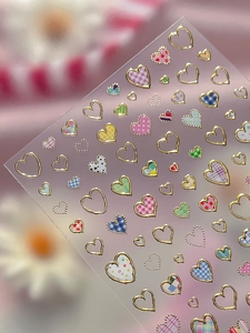 Macro view of silver heart nail art stickers featuring colorful plaid and floral patterns