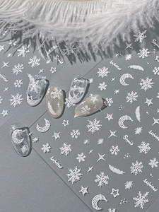 Detail of 3D embossed white snowflake and star nail stickers on transparent tips
