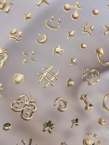Macro shot of 3D gold embossed butterfly nail stickers with various fashion symbols