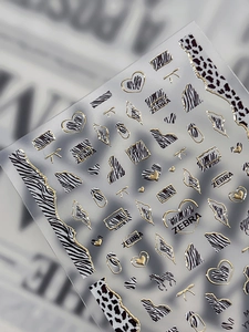 Macro detail of 3D embossed zebra print nail stickers with metallic gold heart edges