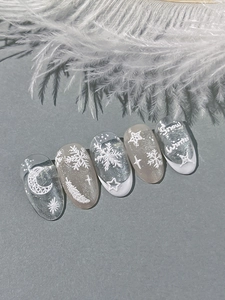 Macro shot of winter press-on nails featuring white snow motifs and feather relief textures