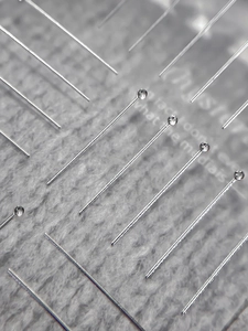 Macro shot of silver metal ball head pins on grey felt texture background