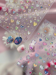 Detail of silver heart nail art stickers with Y2K plaid patterns and application effects