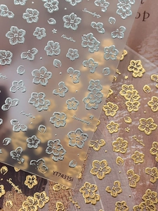Macro view of metallic gold and silver embossed floral nail stickers with relief texture