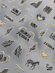 Macro detail of 3D embossed zebra print nail stickers with gold accents and heart patterns