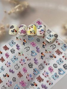 Detail showing embossed cute cartoon animal nail stickers on off-white nail tips