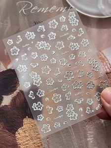 Detailed macro of silver embossed floral nail stickers with metallic stars and petals