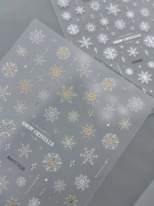 Detailed view of embossed snowflake nail art stickers with white and gold metallic designs