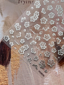 Macro shot of silver metallic flower embossed nail art stickers with 3D floral details