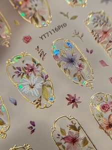 Detailed macro view of vintage floral nail art stickers with gold frames and holographic finish