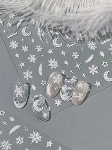 Detailed white embossed snowflake nail art stickers with feathers and stars on false nails