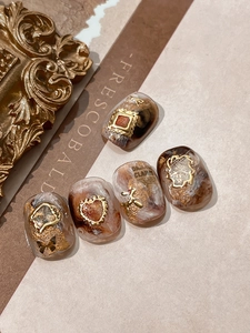 Macro view of amber marble nail stickers with vintage gold relief frames and bow charms