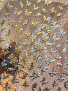 Dettaglio degli adesivi per unghie farfalla 3D oro e argento con consistenza metallica