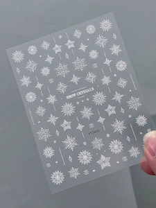 Macro detail of white 3D snowflake nail stickers with starburst patterns for Christmas