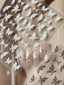 Detailed macro view of 3D embossed butterfly nail stickers in white and black tones