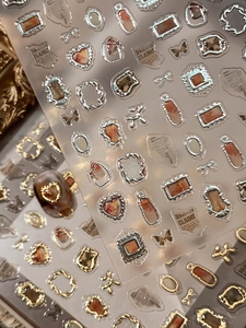 Macro shot of vintage gold embossed amber nail stickers with metallic frame designs