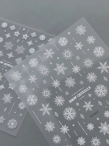 Detailed macro view of 5D embossed white snowflake nail stickers with crystal patterns