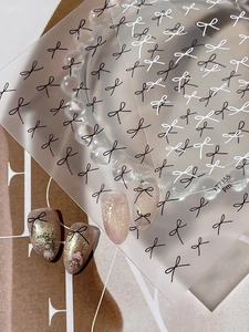 Detail of minimalist bow nail stickers featuring black and white fine lines on nail tips