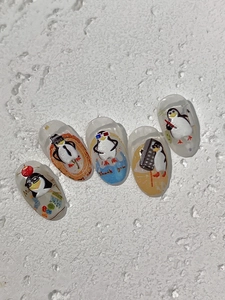 Détail de stickers nail art pingouin 3D avec expressions amusantes sur faux ongles