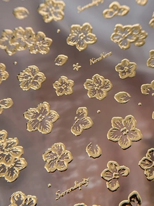 Macro shot of 3D embossed gold floral nail art stickers with metallic texture finish