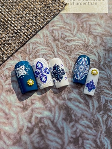 Close-up of embossed blue and white porcelain nail stickers with 3D floral ornaments