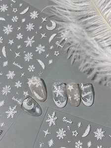 Detail of 3D embossed winter nail stickers featuring white snowflakes and feathers