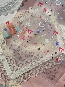Détail de stickers 3D pour ongles avec nœuds roses, étoiles et cœurs sur faux ongles