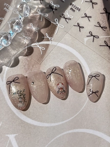 Detailed view of cat eye press-on nails with black bow and vintage character decals