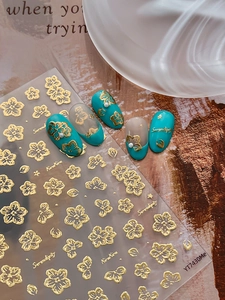 Macro detail of 5D gold embossed floral nail art stickers with 3D cherry blossom designs