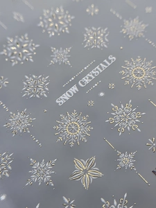 Macro view of 5D embossed snowflake nail stickers with gold and silver snow crystals