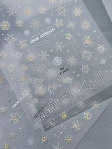 Close-up of white and gold embossed snowflake nail stickers for winter nail art designs