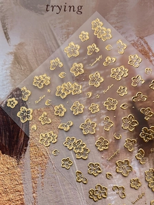 Macro view of 3D metallic gold cherry blossom nail stickers with Serendipity lettering