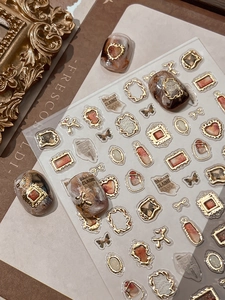 Detail of vintage gold-embossed nail art stickers featuring butterfly and frame motifs