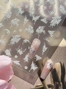 Detailed macro view of 5D white embossed rose and butterfly nail art stickers with relief texture