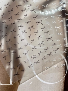 Macro view of minimalist black and white butterfly bow nail stickers on transparent film