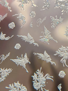 Macro detail of 3D embossed nail stickers featuring white roses and butterfly patterns