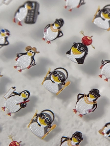 Vue macro de stickers nail art 3D pingouin avec designs de casques et lunettes mignons