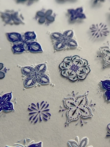 Macro view of 3D embossed blue and white floral nail art stickers with textured details