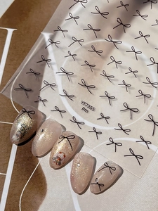 Detail of YT7355 minimalist black bow nail stickers applied on glitter nude nails