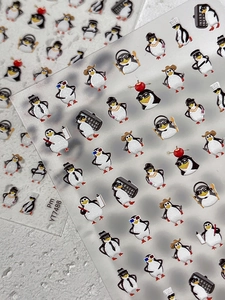 Détail de stickers à ongles pingouin mignons avec des paillettes et divers accessoires