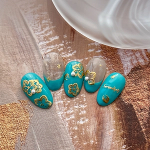 Turquoise and nude press-on nails with golden embossed floral patterns and Serendipity text