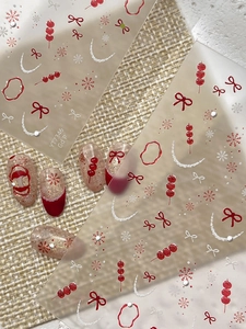 Detailed view of festive nail art stickers featuring red beads and silver snowflakes