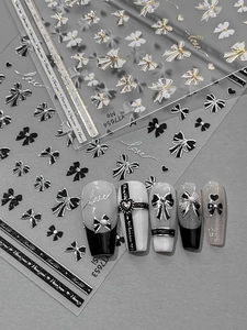 Detailed view of silver bow nail art stickers with 3D embossed heart patterns on tips
