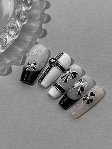 Macro detail of long ballerina nails with 3D bows, pearls, and silver heart accents