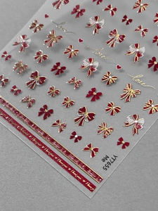 Macro shot of 3D embossed red bow nail stickers with gold heart details and love patterns