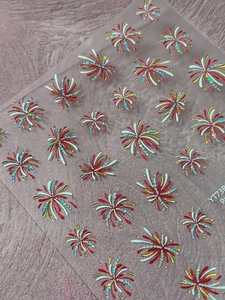 Macro view of gold foil firework nail art stickers with red and white glitter details