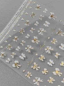 Macro view of embossed nail stickers featuring gold and white bows and hearts
